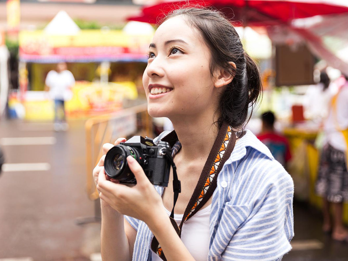 Teenaged student in a market holding a camera